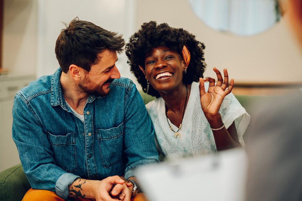 Happy couple smiling and laughing during a couples counseling session, reflecting the positive outcomes of therapy and relationship intensives with Dr. Belle