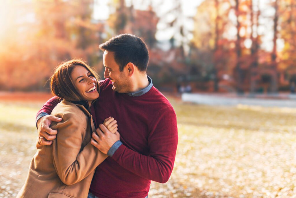 A joyful couple laughing and embracing outdoors in warm autumn light — reflecting the renewed trust, connection, and intimacy couples experience after Dr. Belle's Las Vegas attachment-based couples therapy intensive.