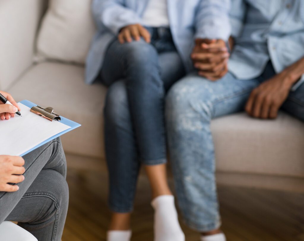 A couple sitting together during a couples therapy session in Las Vegas while therapist Dr. Belle takes notes, licensed marriage and family therapist