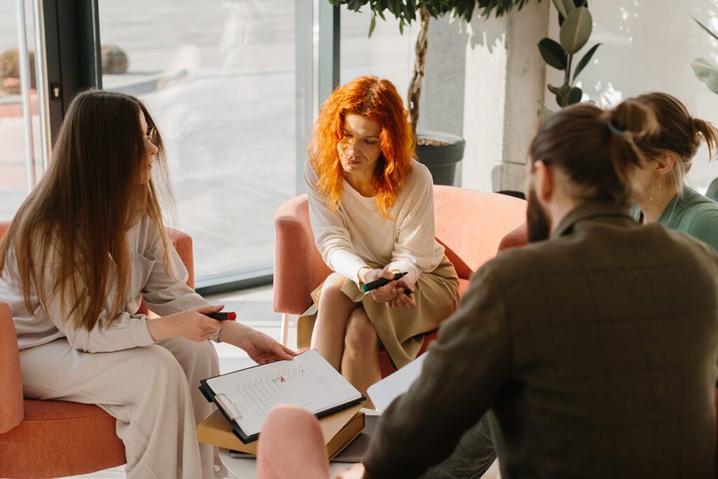 Small group of professionals engaged in a business coaching and consulting session with Dr. Belle, discussing employee culture and workplace relationships