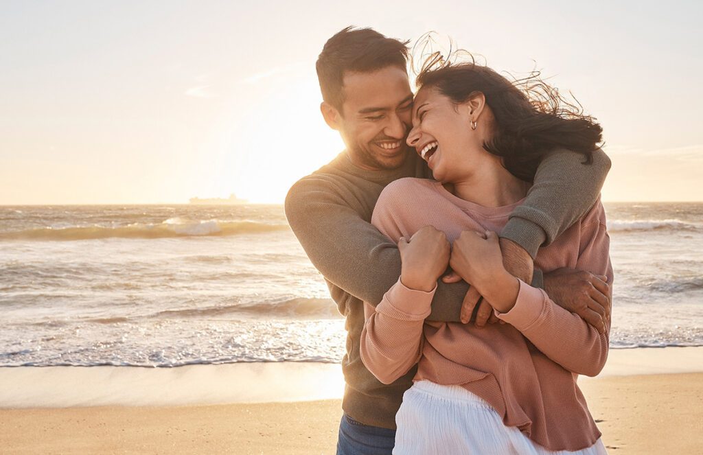 A couple laughing and embracing on a sunlit beach — symbolizing the emotional safety, joy, and deep reconnection couples rediscover through Dr. Belle's EFT-based couples therapy intensives in Las Vegas.