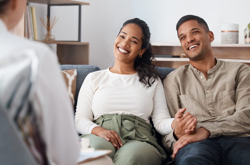 A happy couple smiling and holding hands during a faith-based Christian marriage counseling session in Las Vegas with Dr. Belle, licensed marriage and family therapist