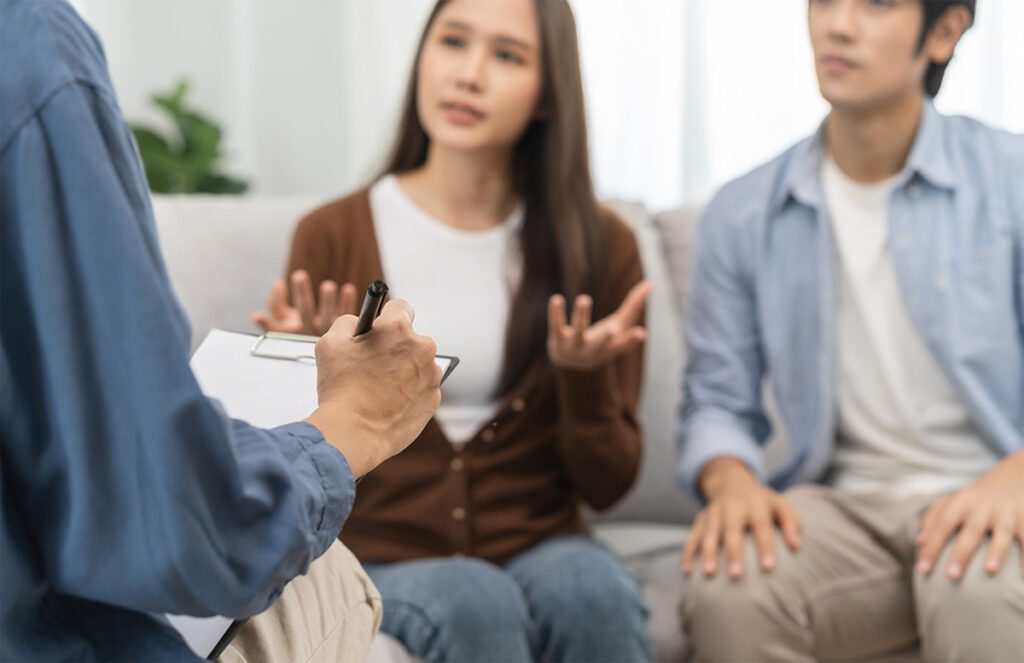 A young couple openly expressing their feelings and concerns during a couples therapy session with a licensed therapist taking notes in Las Vegas, NV, illustrating the safe and supportive environment for honest communication and conflict resolution.