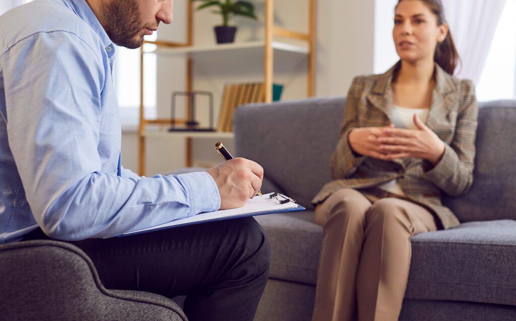 Therapist writing notes on a clipboard while a woman shares during an individual therapy session in Las Vegas, NV, receiving professional personal counseling and mental health support